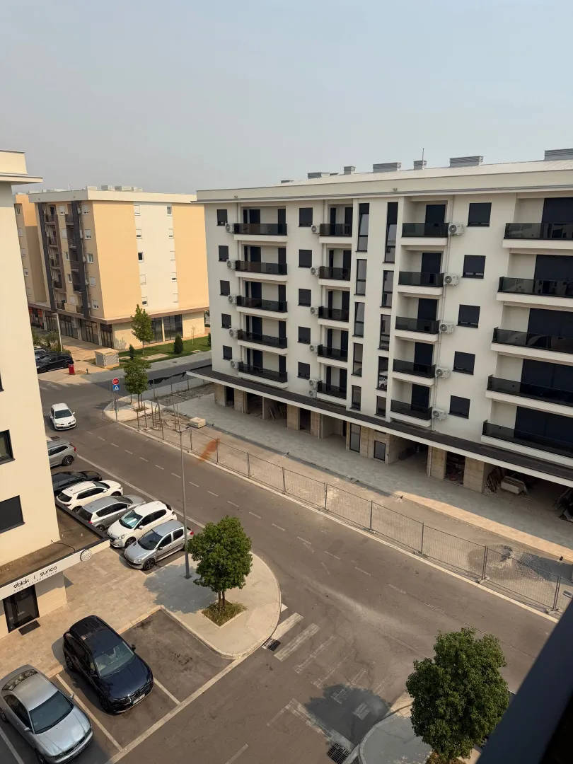 View from the terrace of residential buildings and a street with parking.