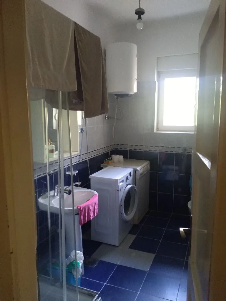 Small bathroom with a sink, washing machine, and blue tiles.