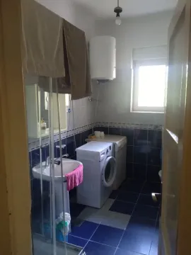 Small bathroom with a sink, washing machine, and blue tiles. - image 3