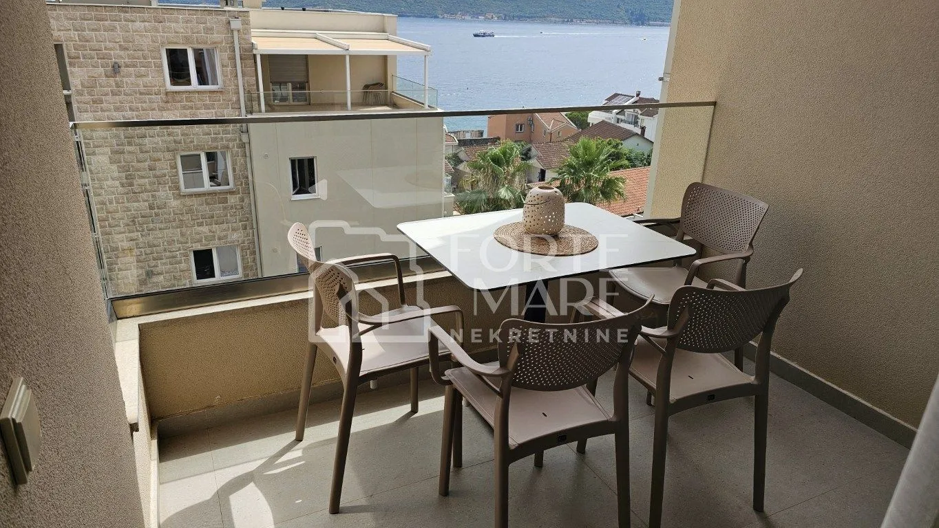 Namješten balkon sa stolom, stolicama i pogledom na more.