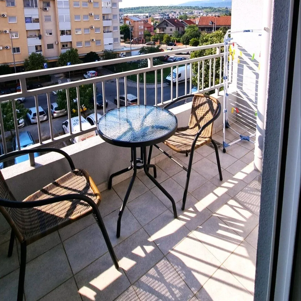 Namješten balkon sa stolom, stolicama i pogledom na naselje.