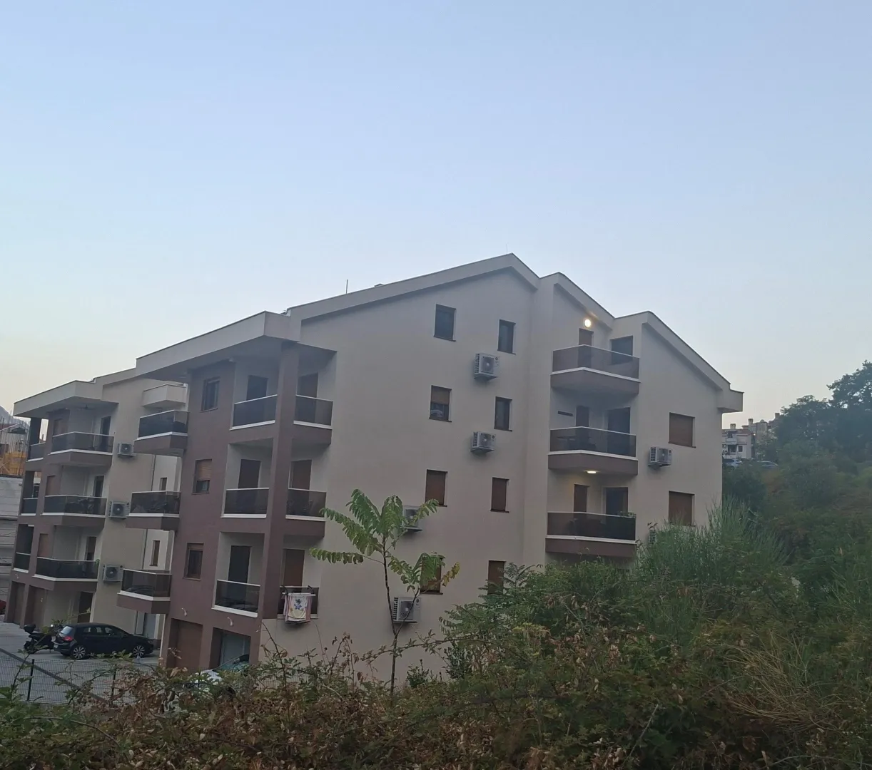Spoljašnji izgled moderne stambene zgrade sa terasama i uređenim okruženjem.