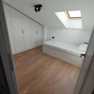 Small bedroom with a bed, built-in wardrobe, and a skylight. - image 9