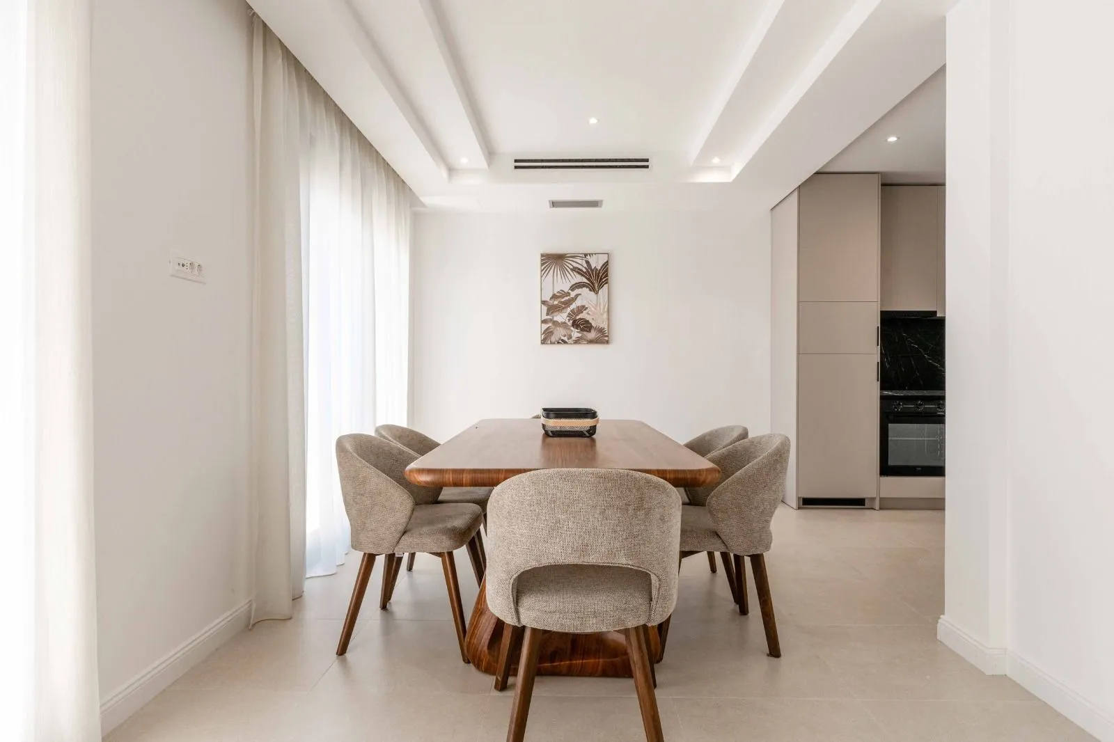 Dining area with a wooden table and upholstered chairs, connected to the kitchen.