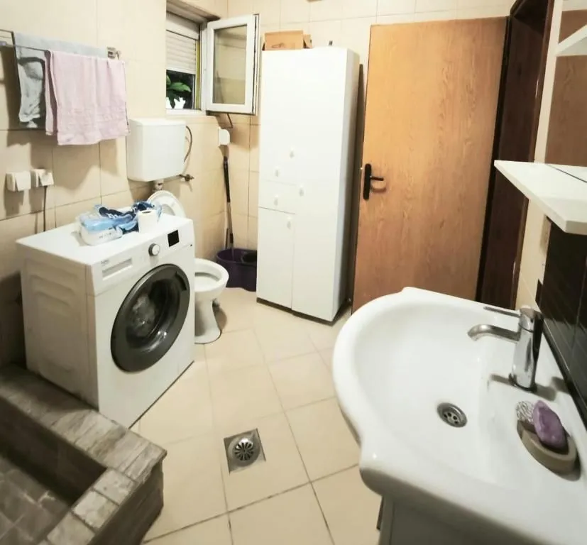Bathroom with washbasin, washing machine, and toilet.