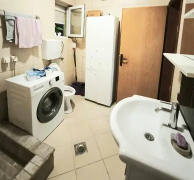 Bathroom with washbasin, washing machine, and toilet. - image 3