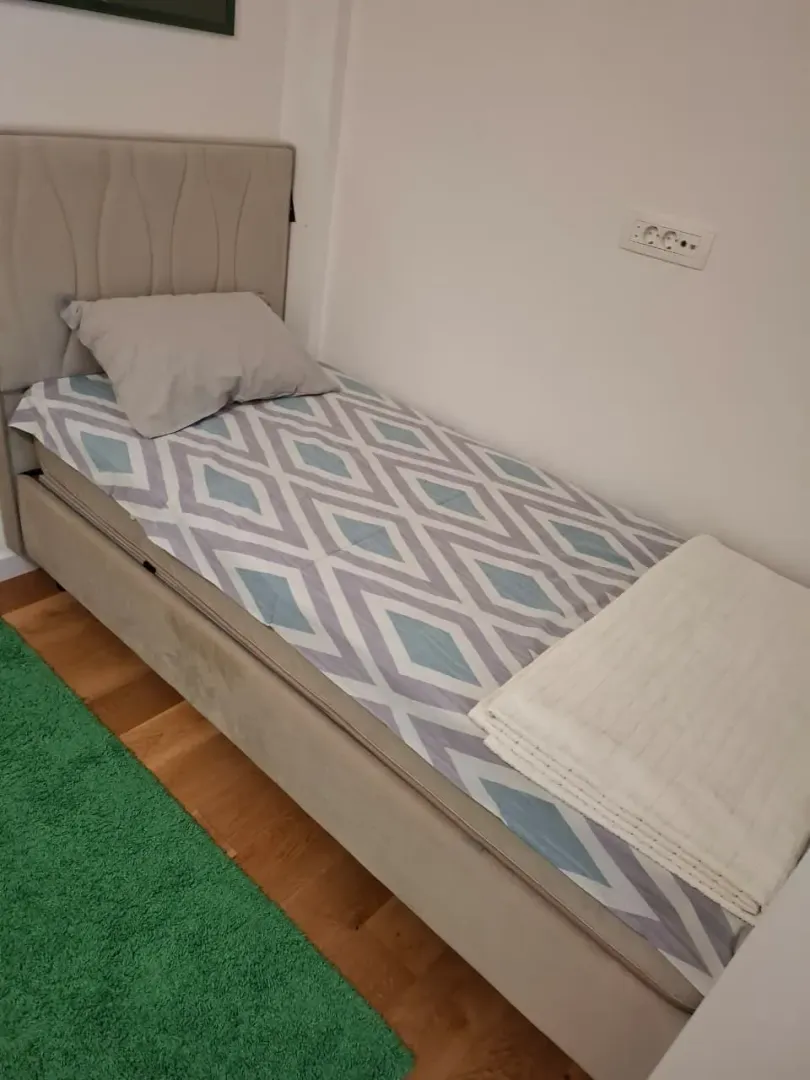 Manja spavaća soba sa krevetom i zelenim tepihom.