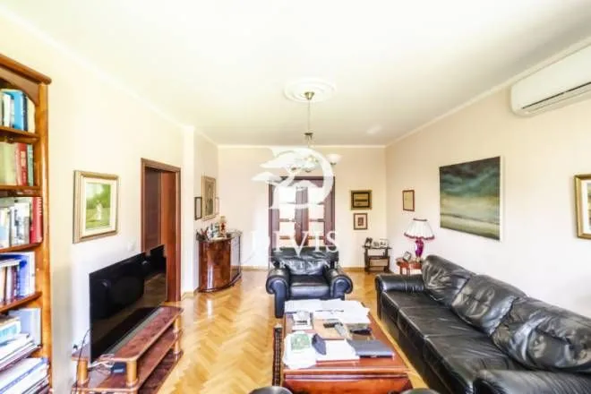 Spacious living room with black leather sofas and wooden flooring.