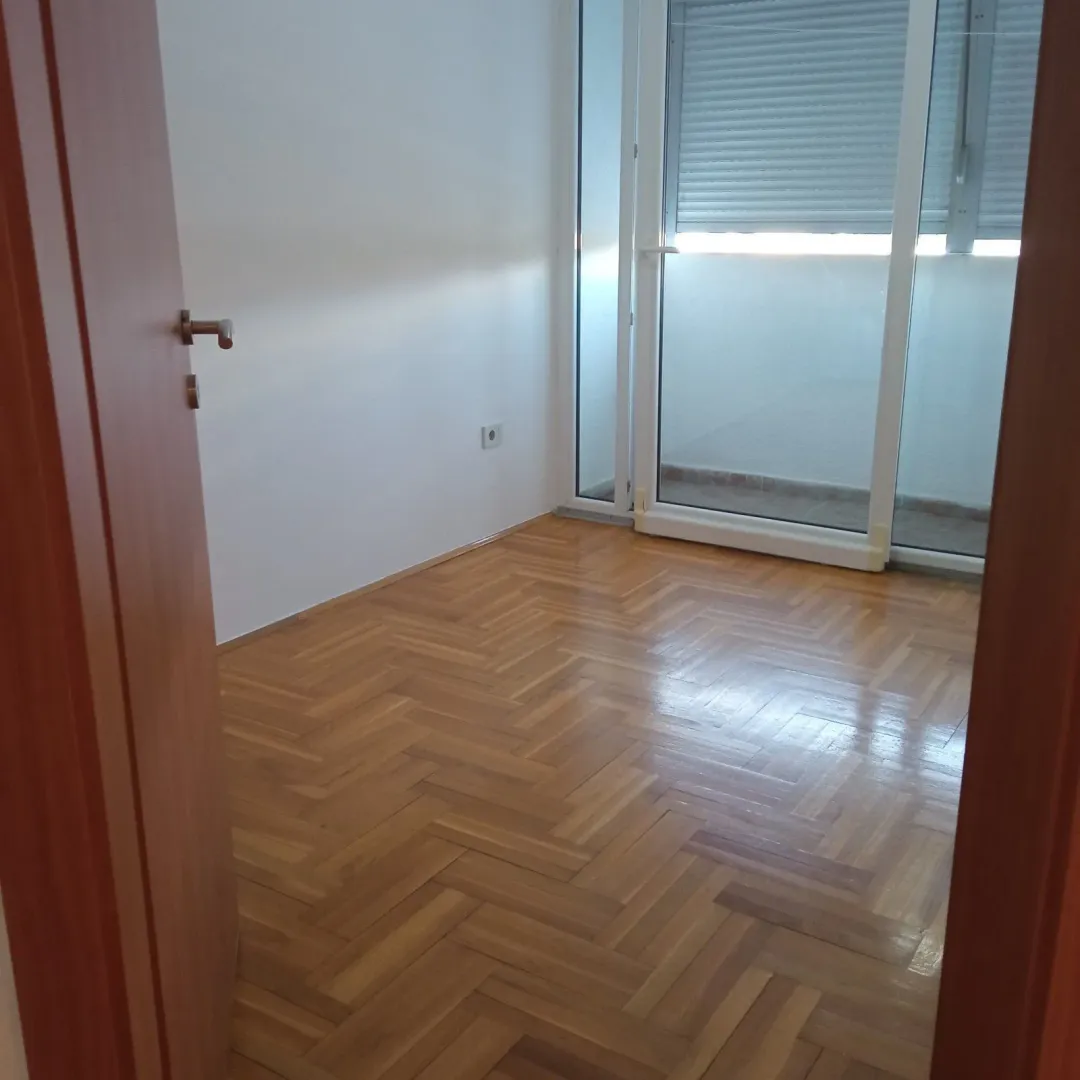 Empty room with parquet flooring and balcony access.