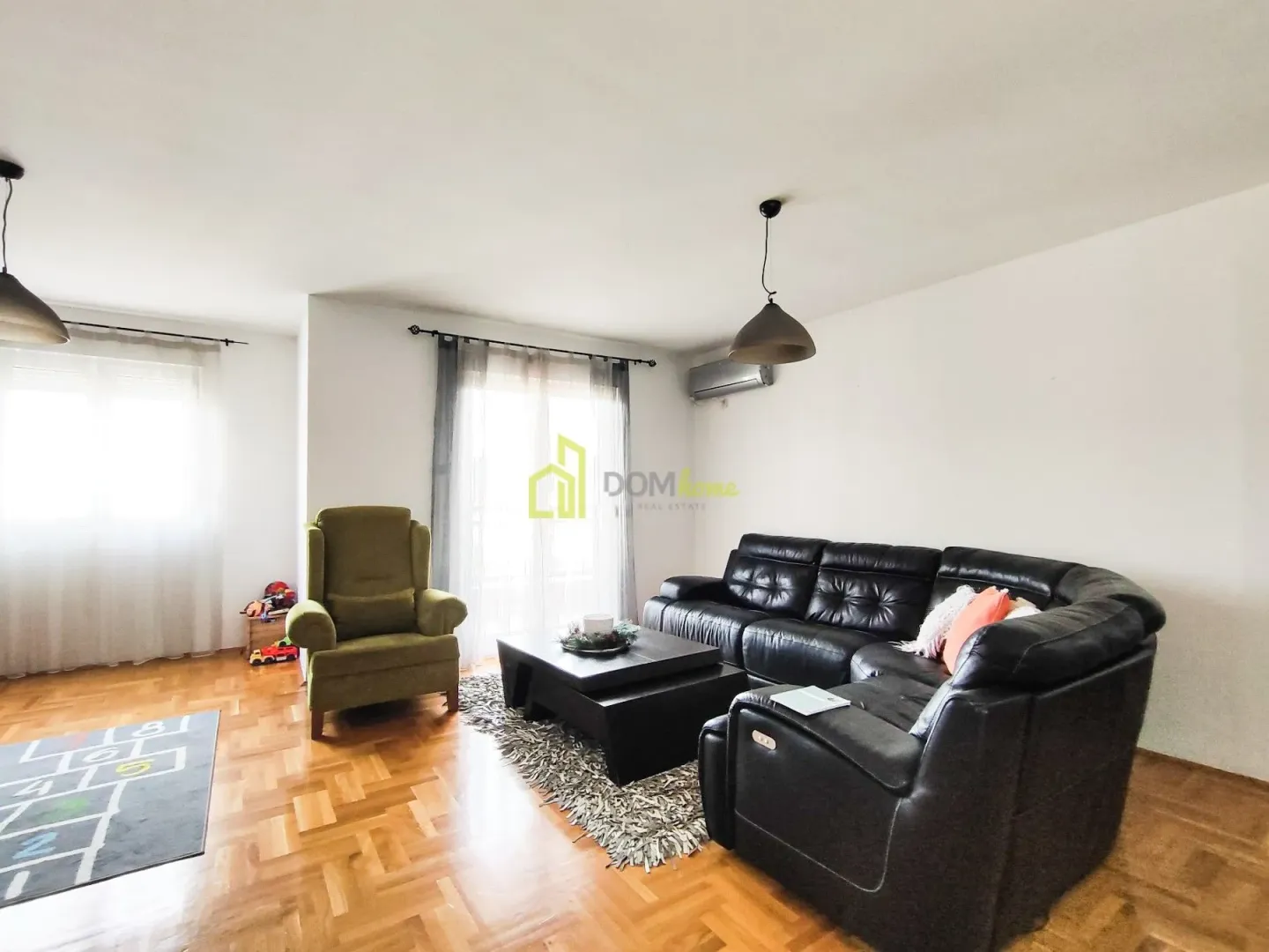 Living room with a black sectional sofa and a green armchair.
