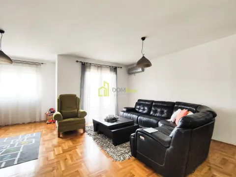 Living room with a black sectional sofa and a green armchair. - image 3