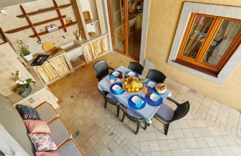 Covered terrace with a dining table and an outdoor kitchen. - image 8