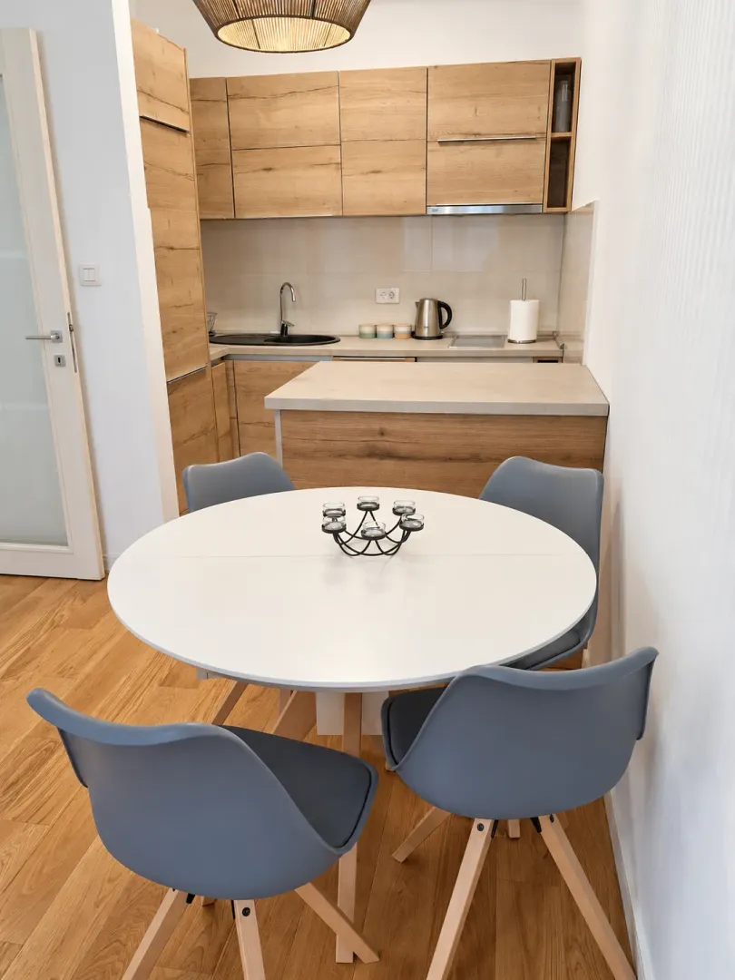 Modern kitchen with dining table and wooden elements.