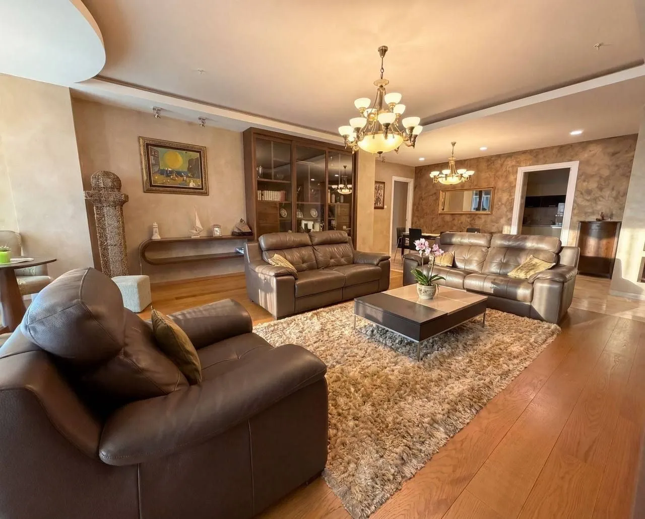 Spacious living room with a seating set and a dining area in the background.