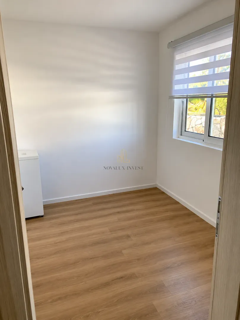 Empty room with laminate flooring and white walls viewed from the doorway.