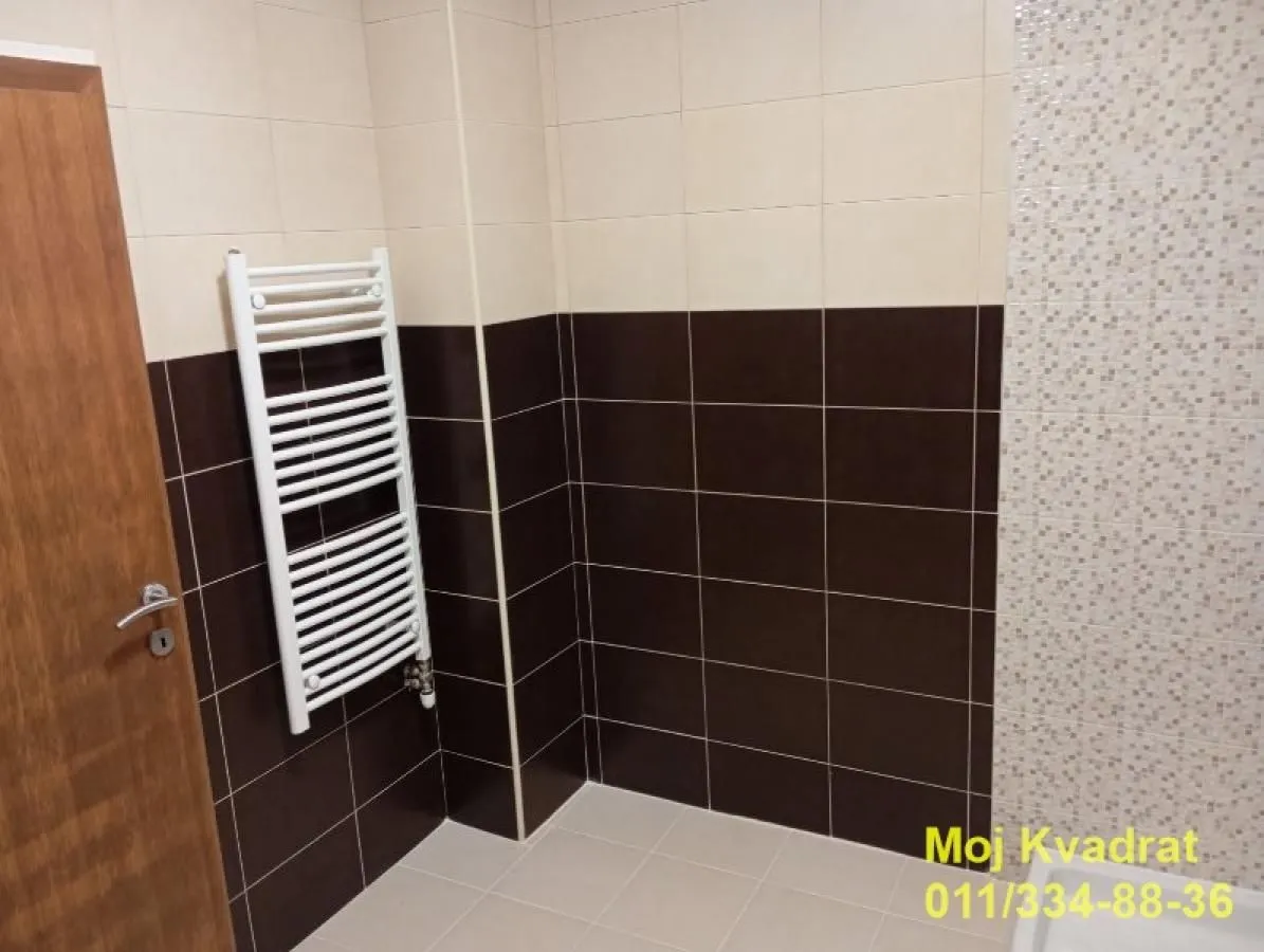 View of the bathroom with tiles and a towel radiator.