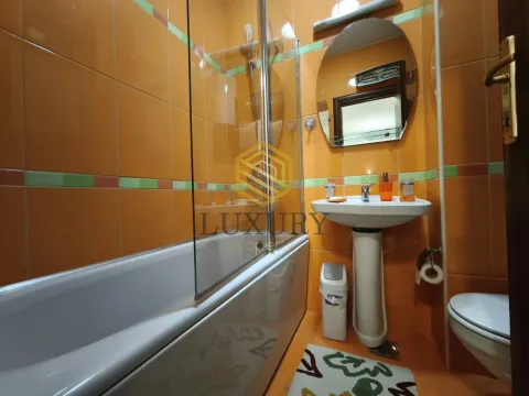 Kupatilo sa kadom, umivaonikom i toaletom, obloženo narandžastim pločicama. - image 18