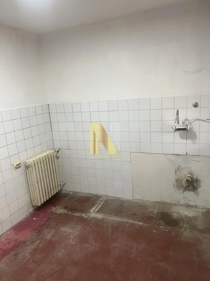 Prazna prostorija sa keramičkim pločicama i radijatorom.