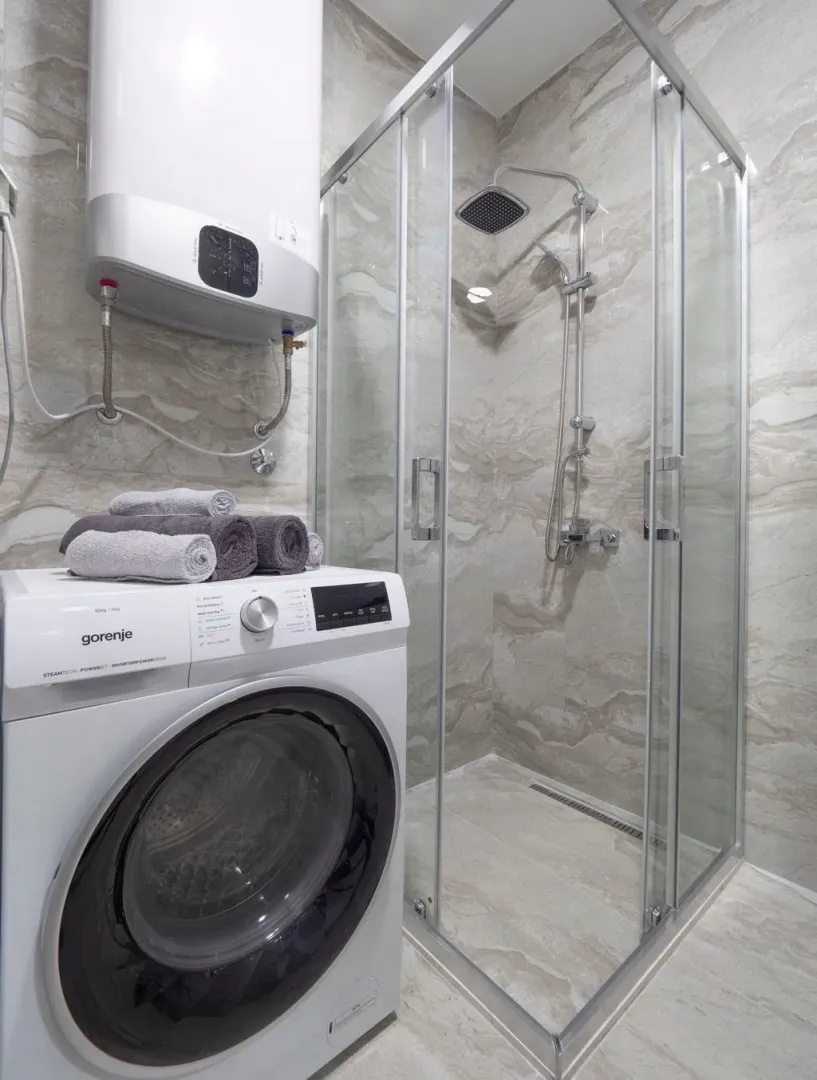 Bathroom with a shower cabin, washing machine, and water heater.