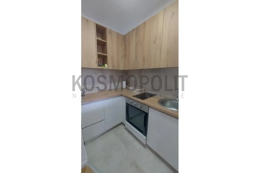 Smaller kitchen with white lower units and wooden upper cabinets.