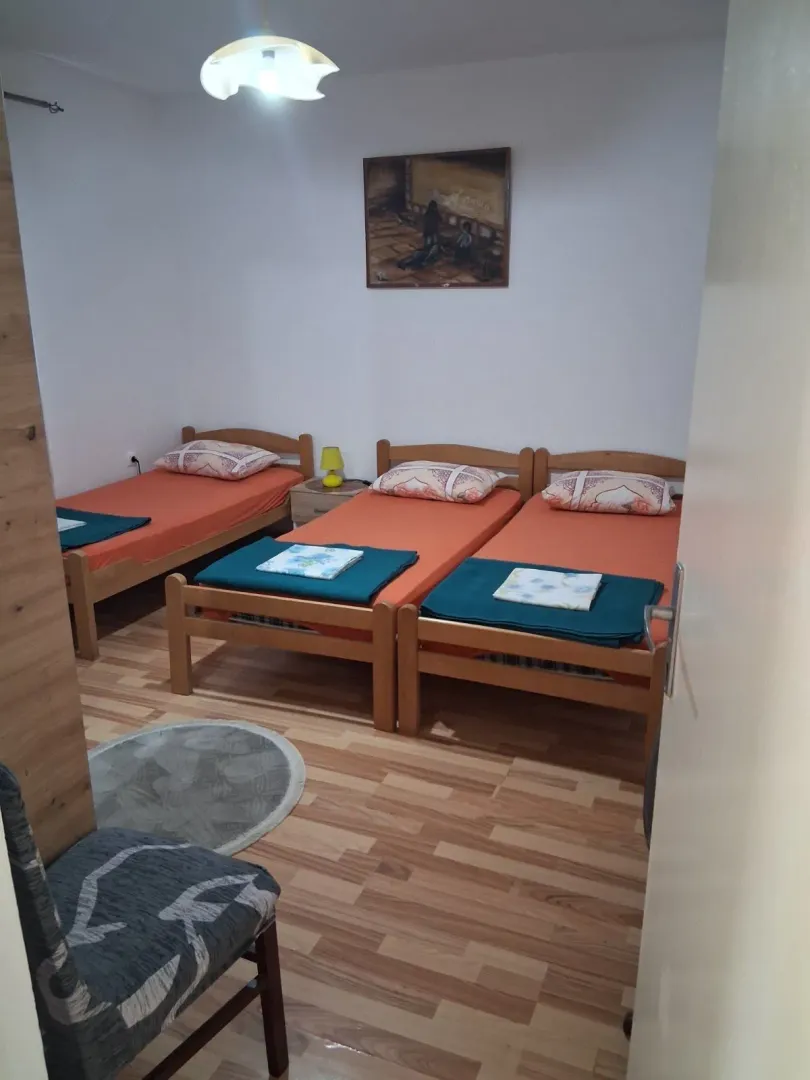 Bedroom with three wooden beds and orange bedsheets.