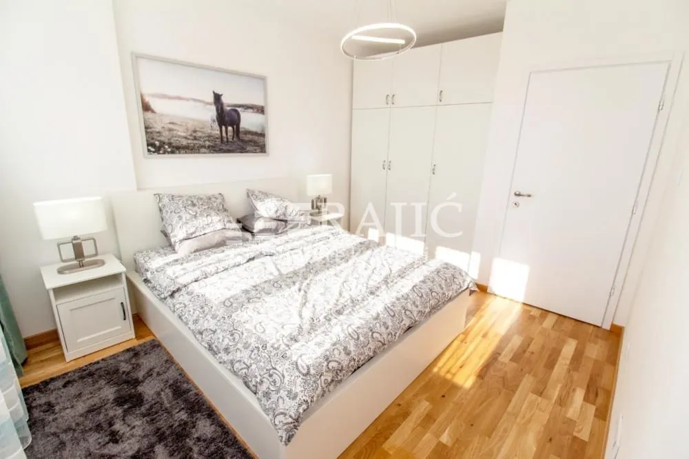 Bright bedroom with a double bed, wardrobe, and white furniture.