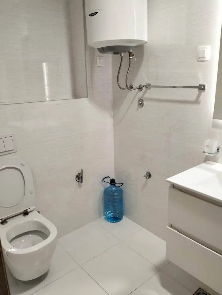 Pogled na kupatilo sa WC šoljom, umivaonikom i bojlerom.