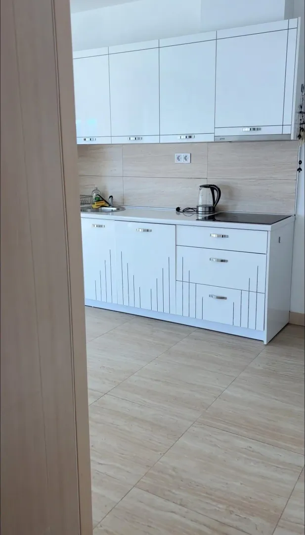 Modern white kitchen with wooden tone cabinets and tiles.