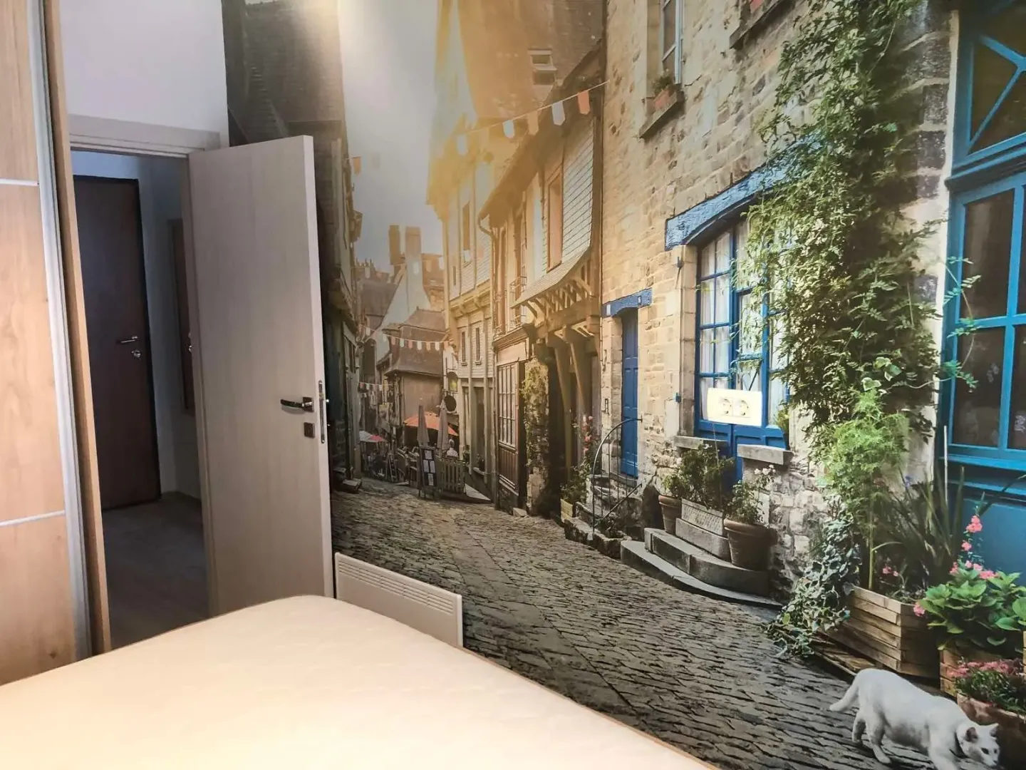 Bedroom with a wall decorated with a street motif wallpaper and an open door.