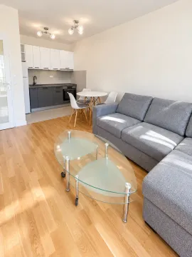Living room with a sectional sofa, dining table, and kitchen in the background. - image 9