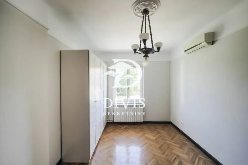 Empty bedroom with a fitted wardrobe, parquet flooring, and an air conditioner.