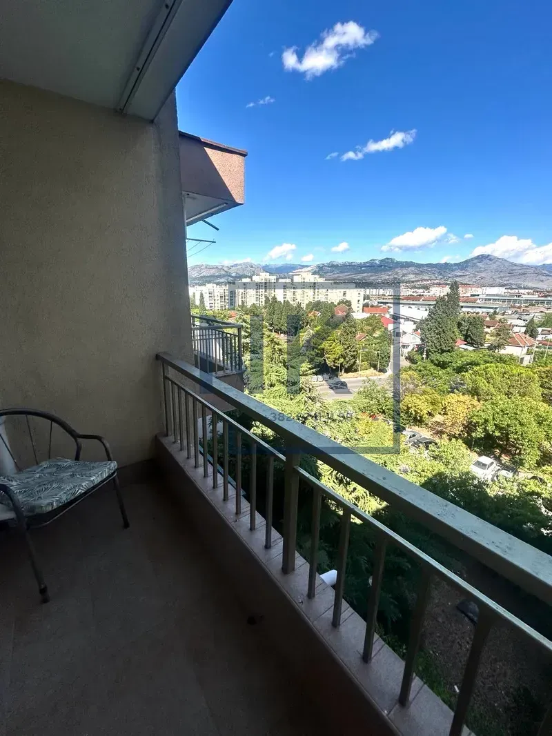 Balkon sa stolicom i pogledom na grad i planine.