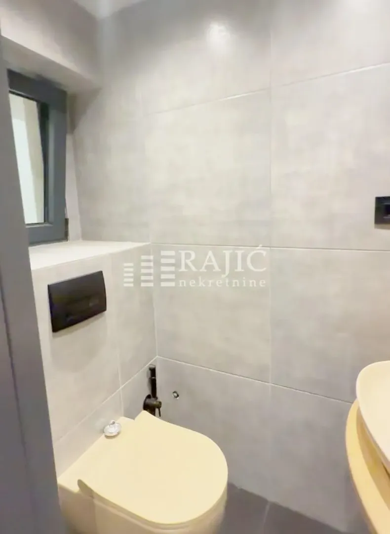 Modern bathroom with gray tiles, toilet, and sink.