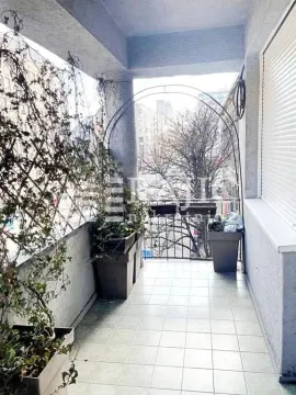Long covered terrace with potted plants and a street view. - image 14
