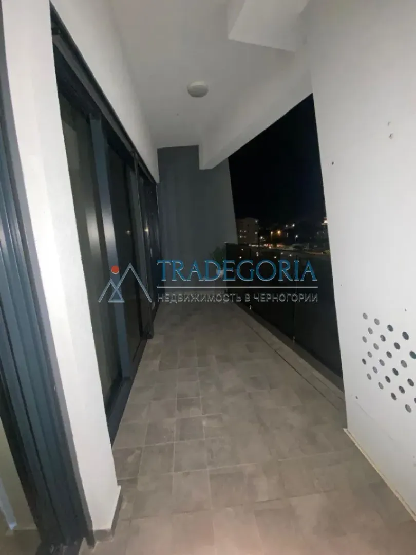 Nenamješten balkon sa pločicama i pogledom noću.