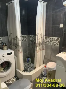 Bathroom with a shower cabin, washbasin, and washing machine. - image 20