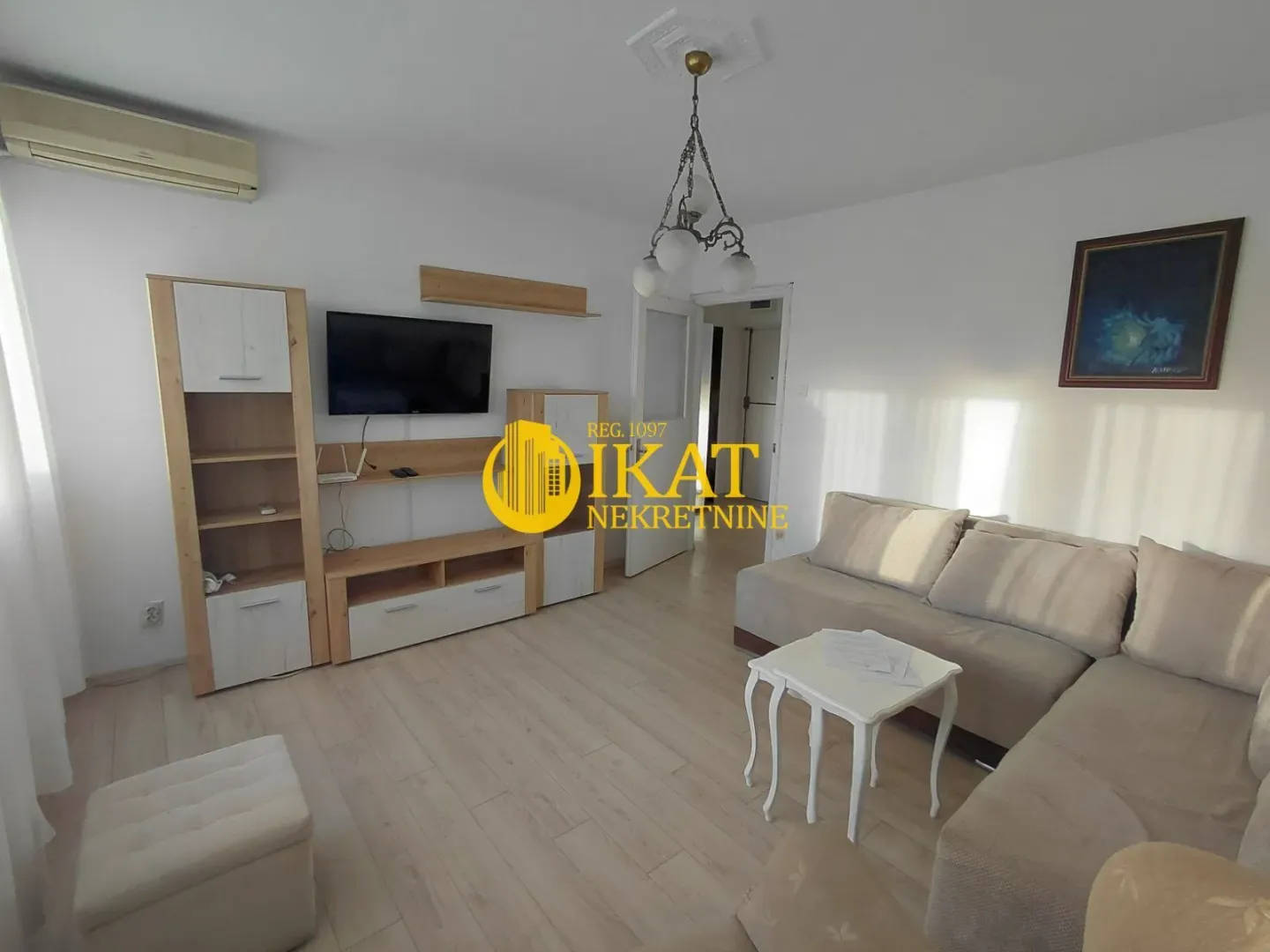 Living room with sofa, TV unit and wooden shelving.