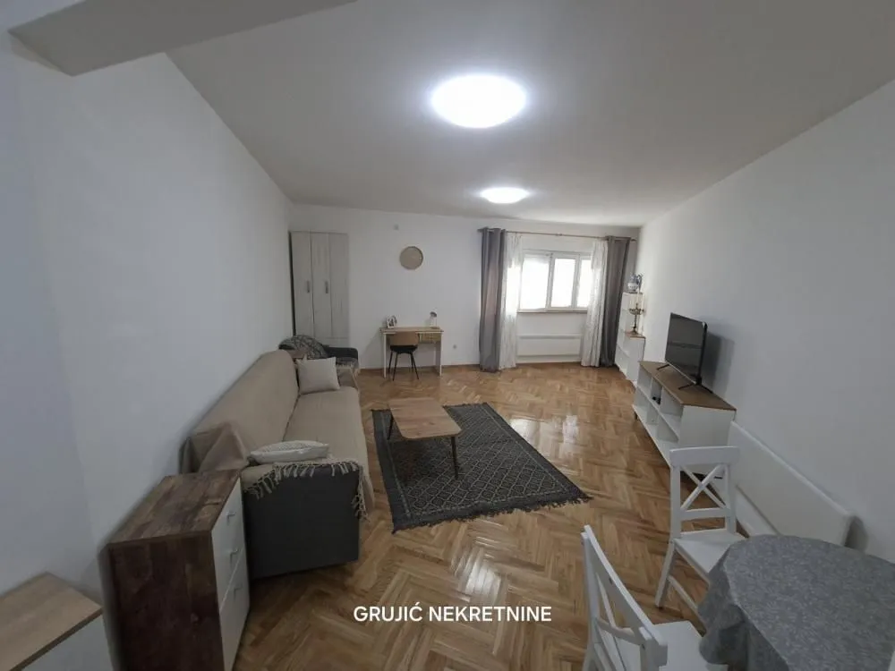 Spacious living room with sofa, TV unit and dining table.