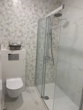 Modern bathroom with a shower cabin and a wall-mounted toilet. - image 6