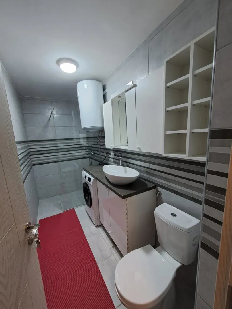 Bright and modern bathroom with a shower cabin and a washing machine.