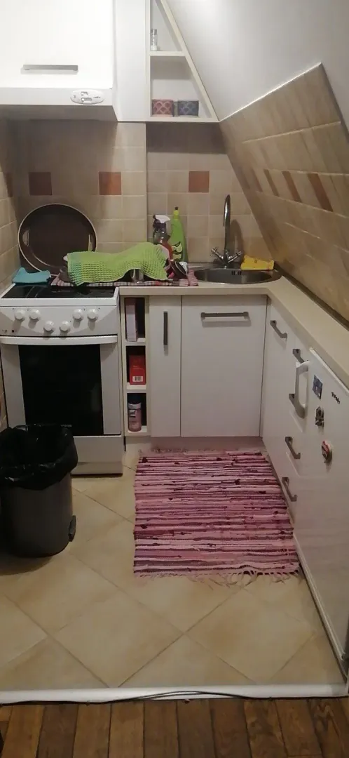 A small kitchen with white cabinets, a stove, and a sink.
