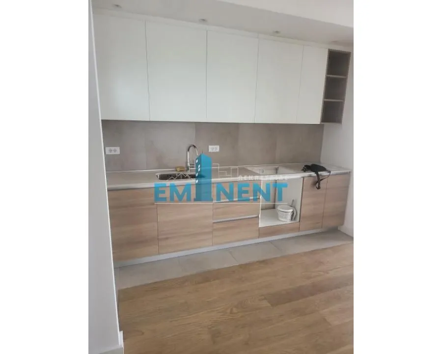 A view of the kitchen with white upper cabinets and wooden lower cabinets.