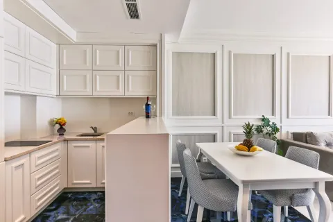 Modern white kitchen with dining area and breakfast bar. - image 5