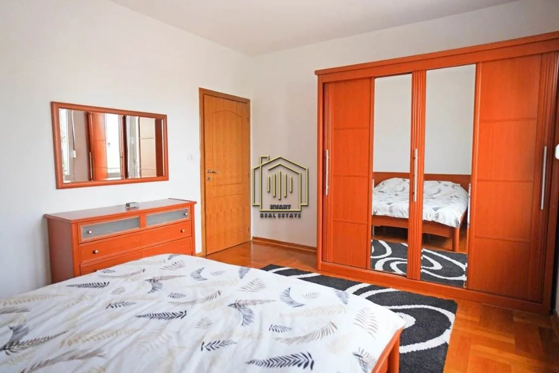 Furnished bedroom with a double bed, large wardrobe, and a dresser with a mirror.