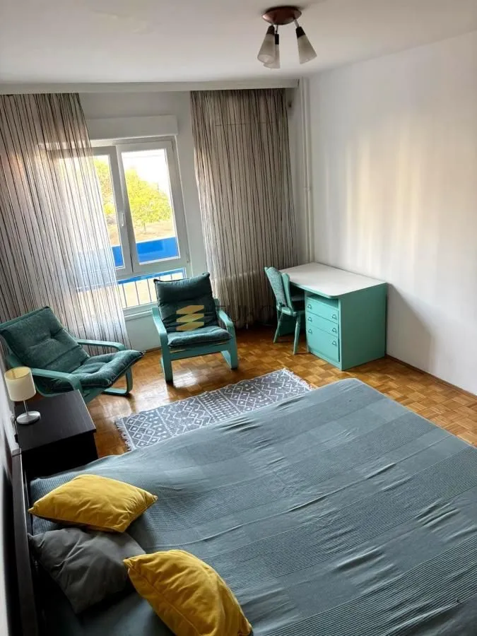 Nameštena spavaća soba sa bračnim krevetom, radnim stolom i foteljama.