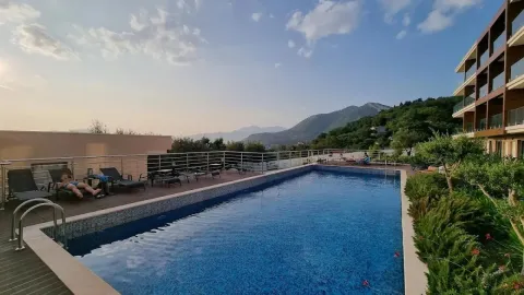 Outdoor swimming pool with sun loungers and views of the surrounding mountains. - image 3
