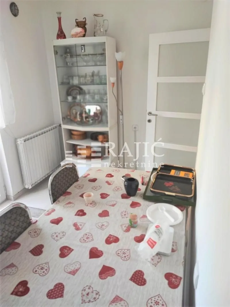 Dining room with a table, display cabinet, and radiator.
