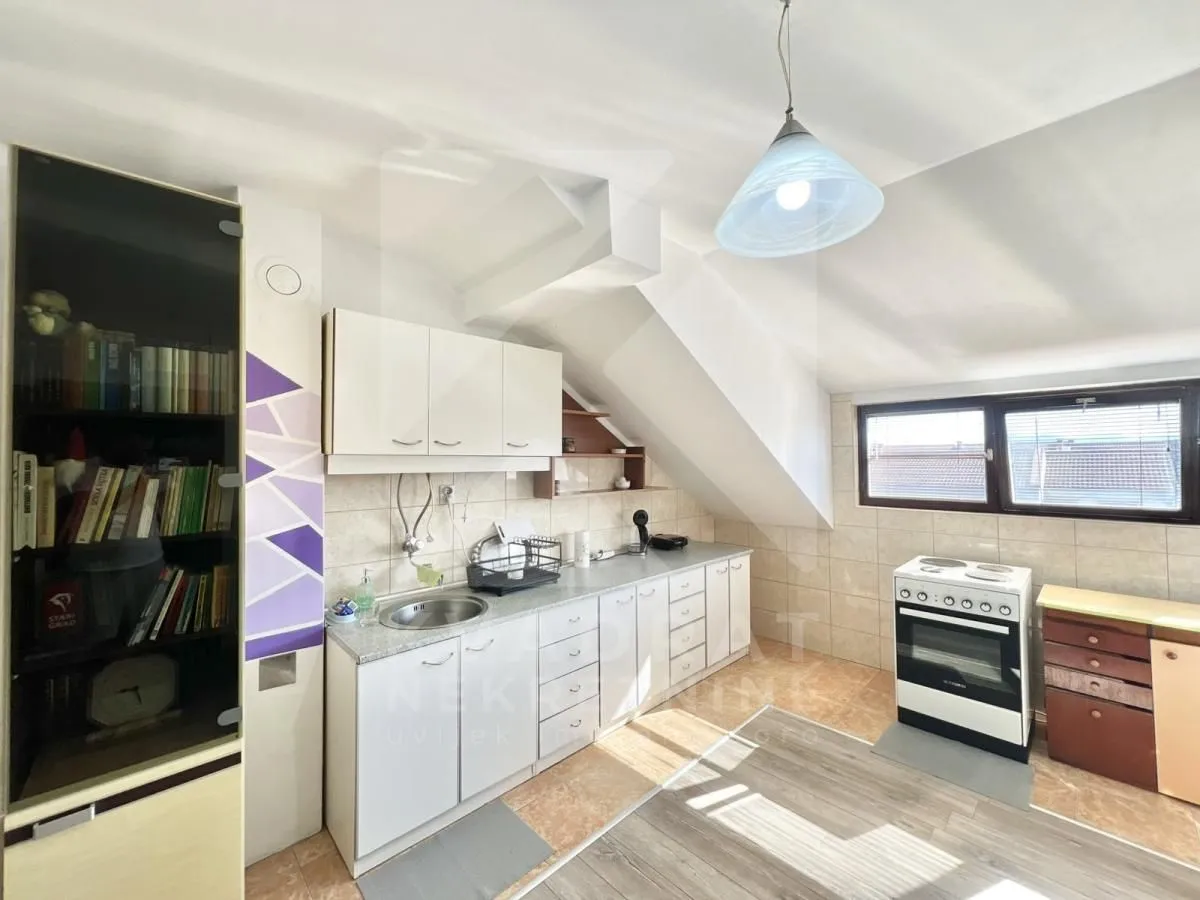 Attic kitchen with white cabinets and a stove.