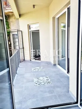 Spacious tiled terrace with metal railing and large balcony doors. - image 13