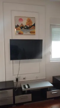Dnevna soba sa televizorom na zidu i komodom. - image 4